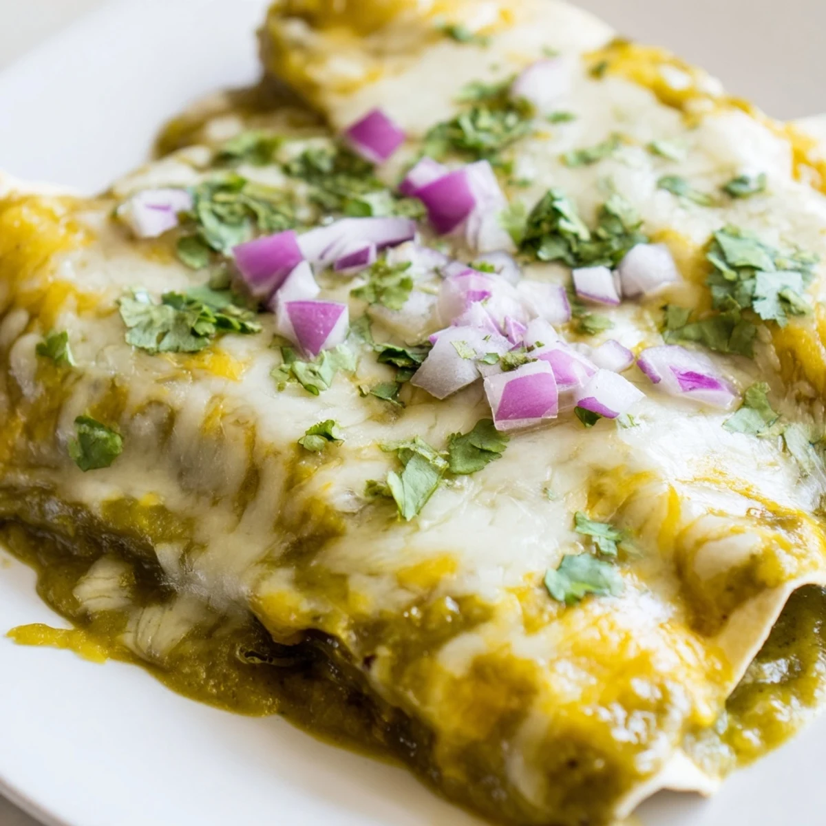 Tender ground beef and sautéed onions fill warm flour tortillas, smothered in a vibrant green chili tomatillo sauce for serving.