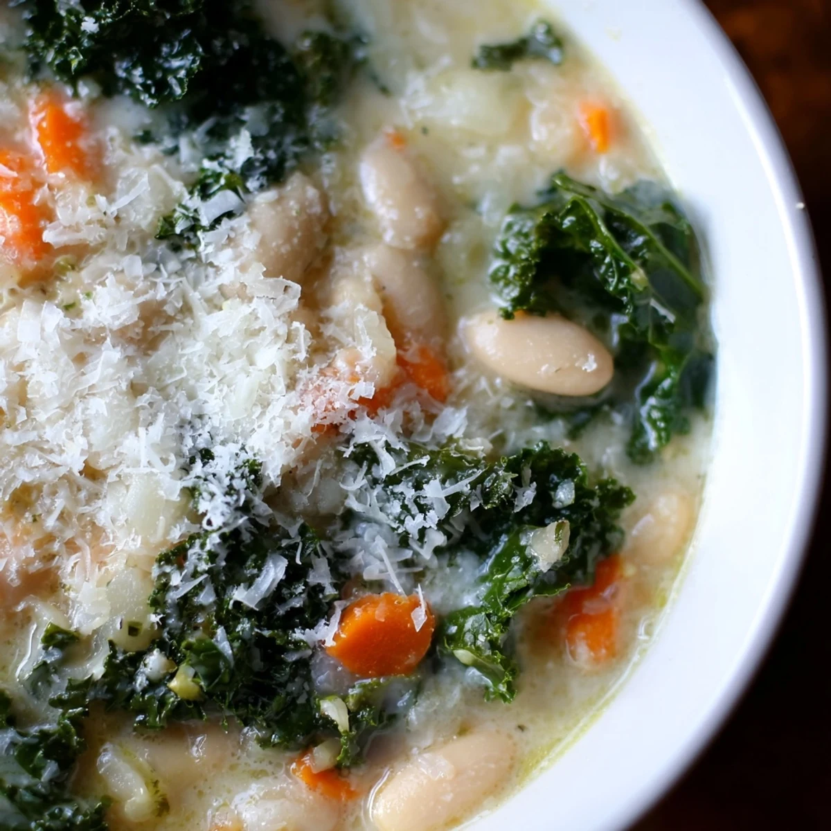 A pot of Creamy White Bean and Kale Tuscany Soup bubbling on the stove. Featuring tender kale and aromatics in a rich, velvety broth.