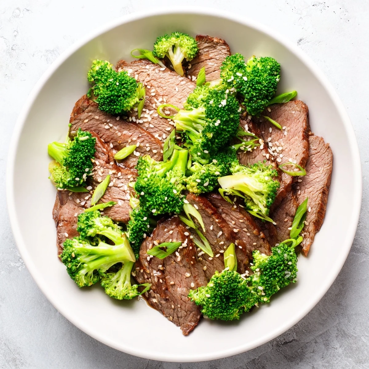A close-up shows tender beef strips and crisp broccoli coated in glossy sauce, topped with sesame seeds for a delicious Keto Friendly Beef and Broccoli Stir Fry with Ginger.