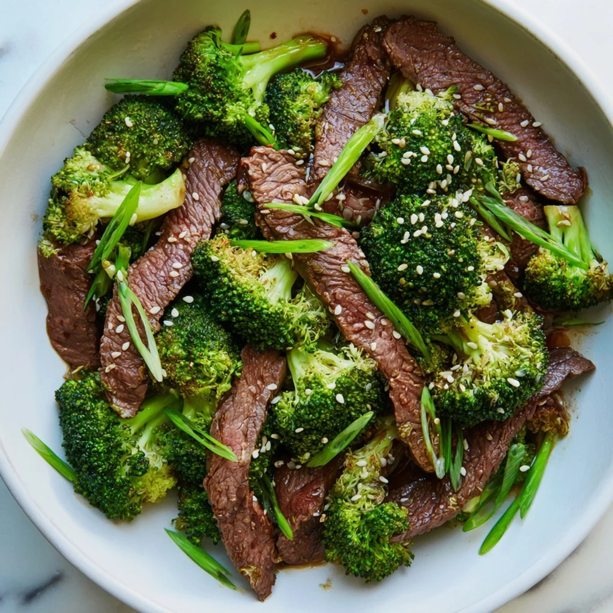 Freshly seared beef and bright green broccoli florets tossed in a savory ginger sauce are served in a white bowl, capturing the essence of Keto Friendly Beef and Broccoli Stir Fry with Ginger.