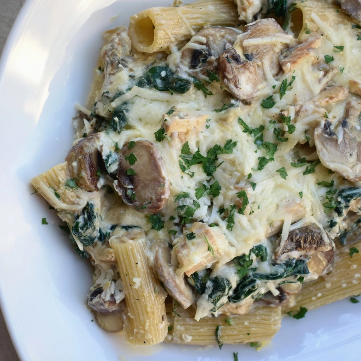 Freshly baked Creamy Mushroom and Spinach Pasta Bake served hot with chopped parsley garnish.
