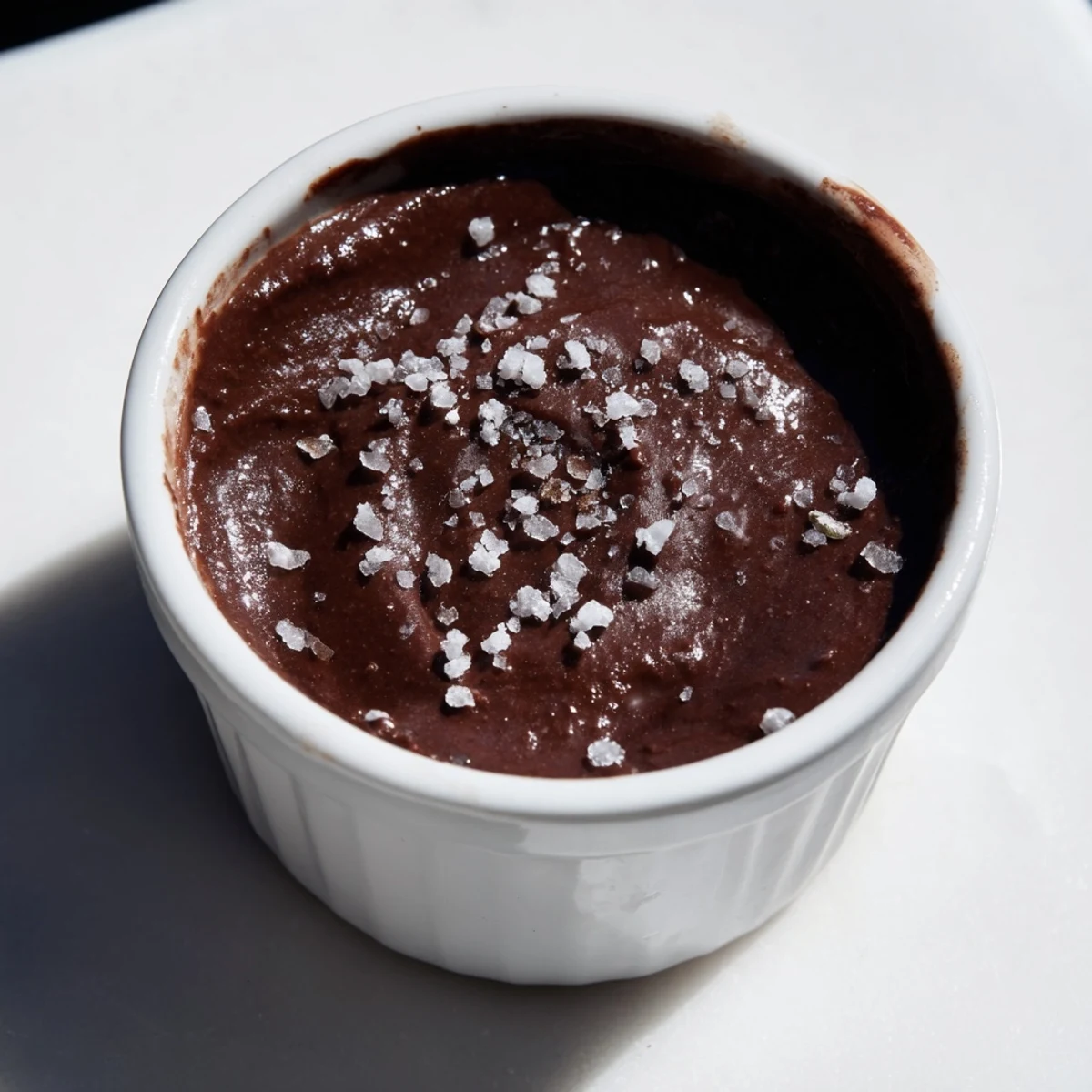 A rich, dairy-free dark chocolate avocado mousse with velvety texture and a sprinkle of sea salt, perfect for a healthy sweet treat.  