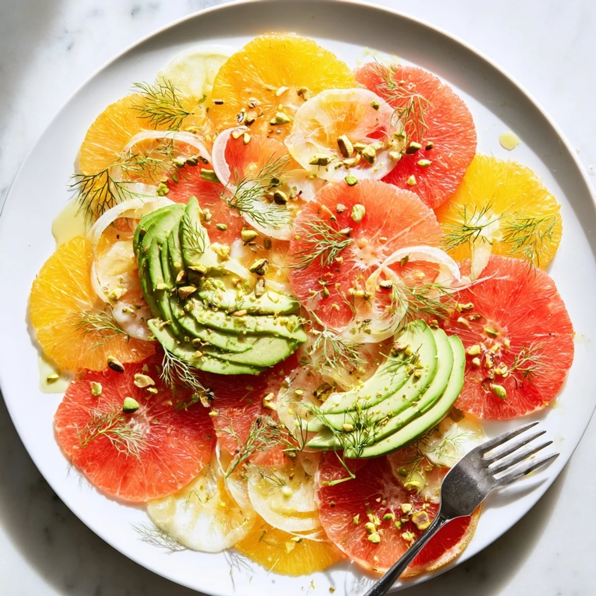 Citrus segments and avocado slices gleam atop this winter citrus salad with avocado and fennel, garnished with pistachios.