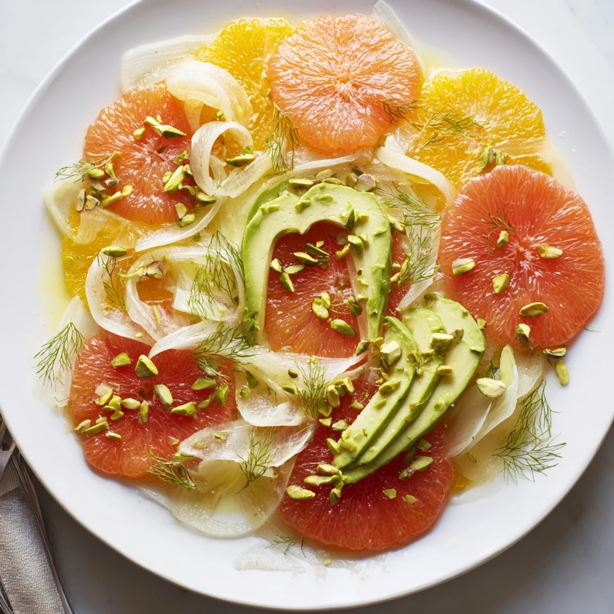 A close-up of shaved fennel, vibrant orange rounds, and avocado in a refreshing winter citrus salad with avocado and fennel.
