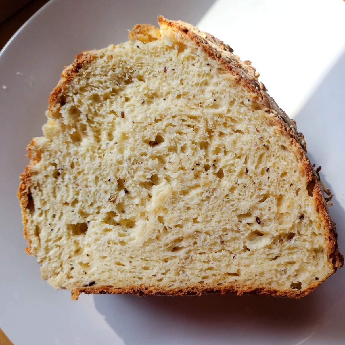 A freshly baked Irish Soda Bread with Caraway Seeds sits on a wooden board with golden crust and visible seeds.