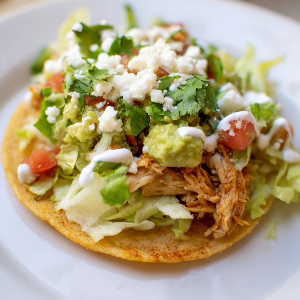 Mini chicken tostadas arranged for a party, showing crunchy tortillas loaded with lettuce, salsa, and lime wedges.