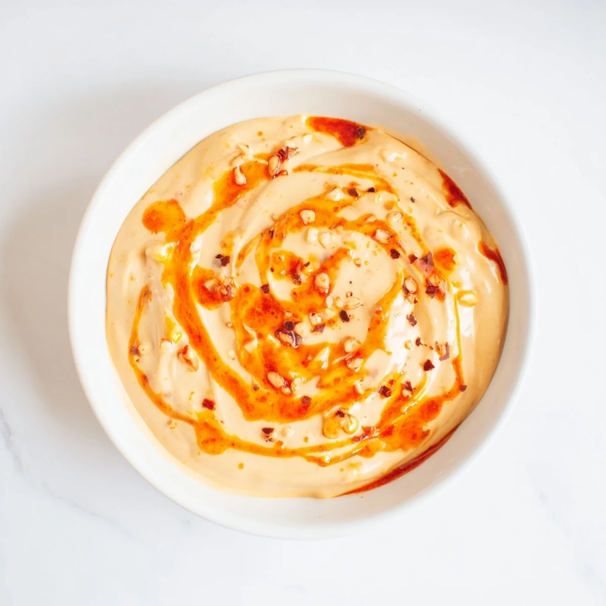 A small jar of Spicy Aioli beside fresh lemon wedges and fries, perfect for a Mediterranean-style dipping sauce.