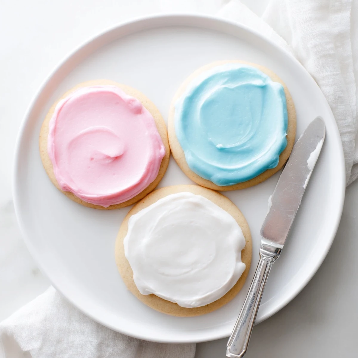 Vibrant Easy Sugar Cookie Frosting in pastel colors glazes decorated cookies on a cooling rack with a rustic kitchen counter background.