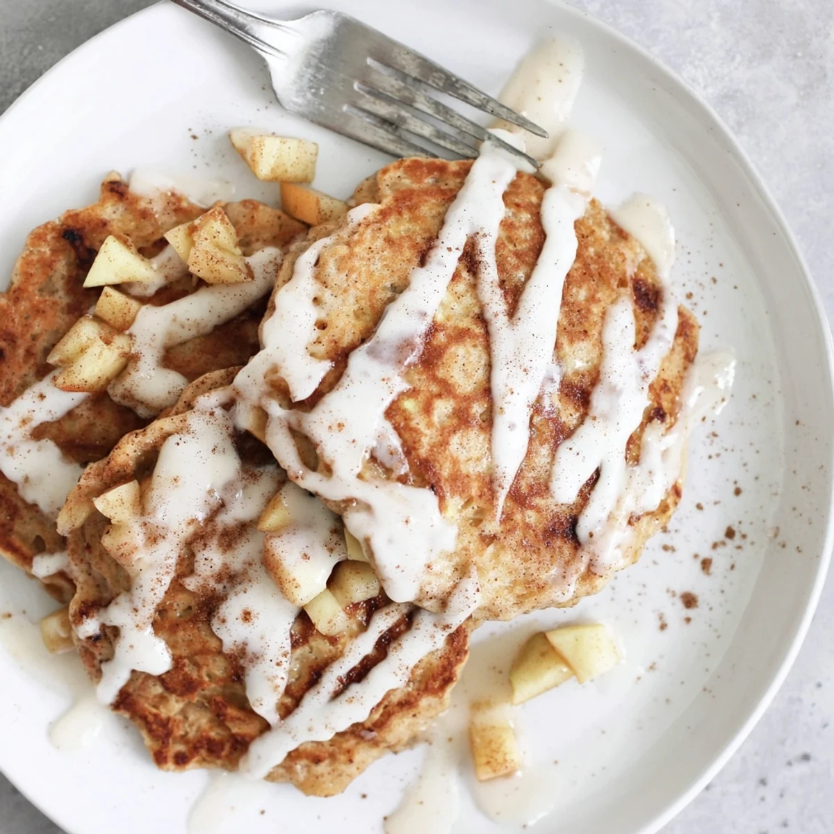 Freshly cooked Apple Fritter Pancakes with diced apples and cinnamon sugar, ready to be drizzled with sweet glaze.
