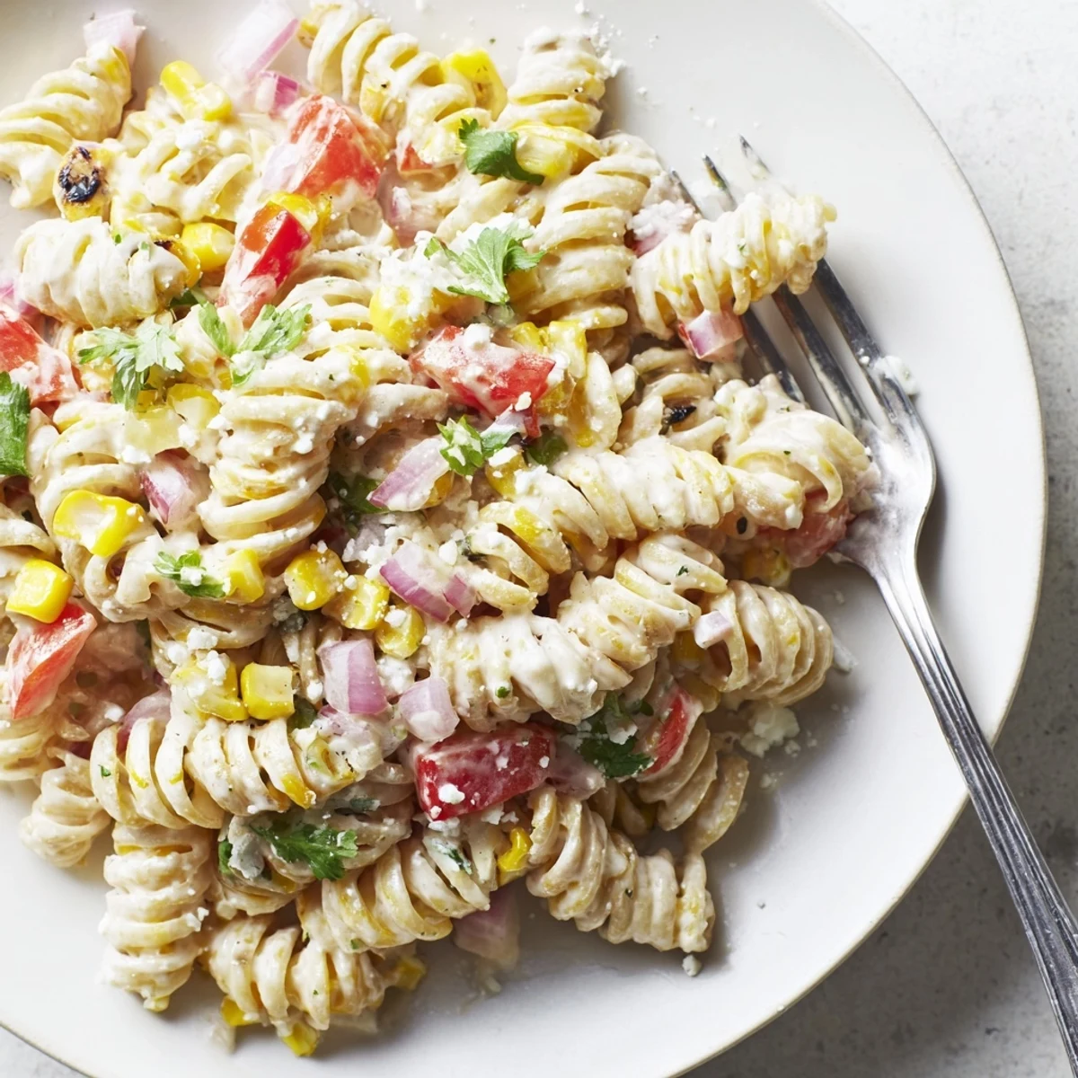 A chilled Juicy Street Corn Pasta Salad with crumbled feta, smoky chili seasoning, and bright lime for summer picnics.