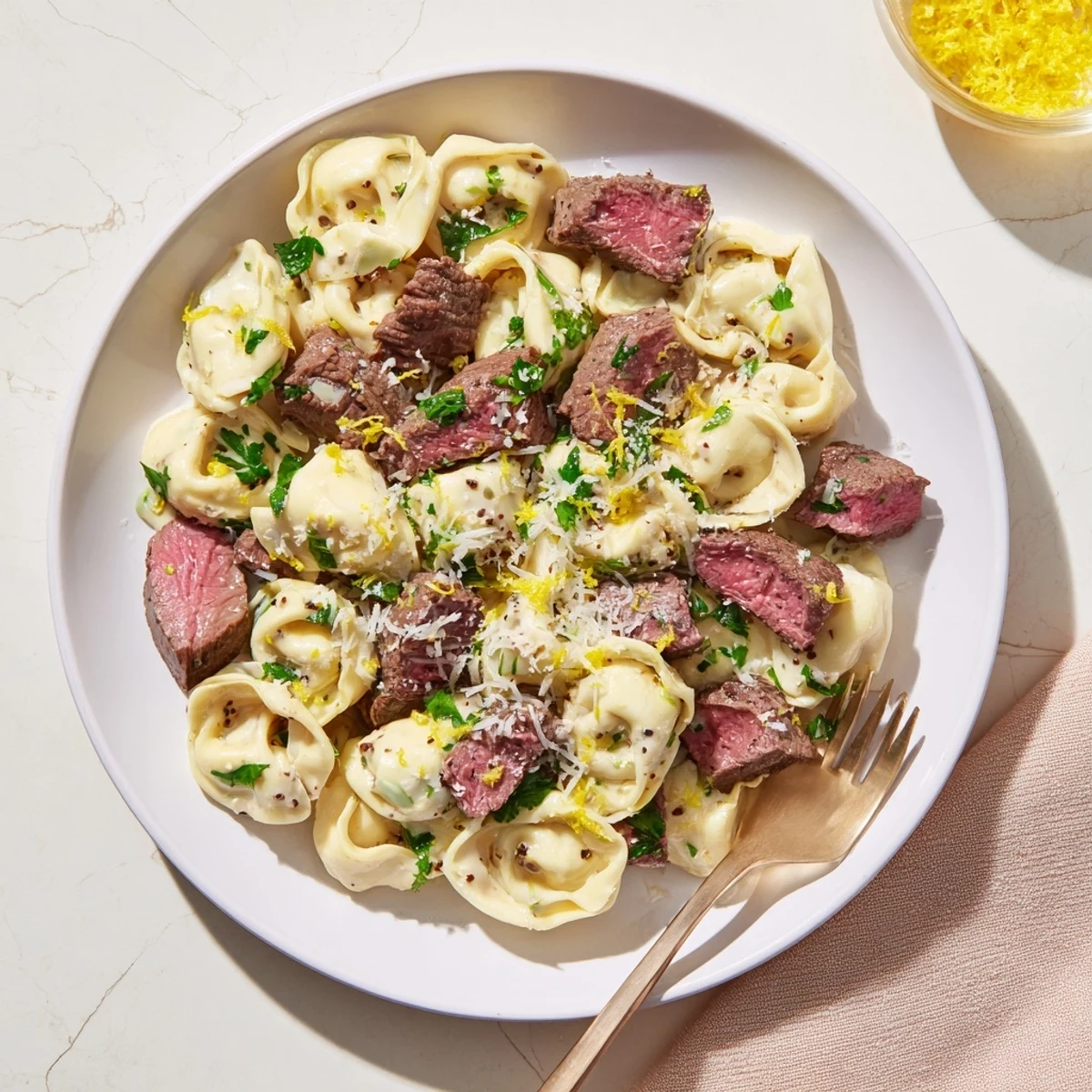 Golden seared steak slices and cheese tortellini swimming in cracked garlic creamhouse sauce with fresh parsley garnish