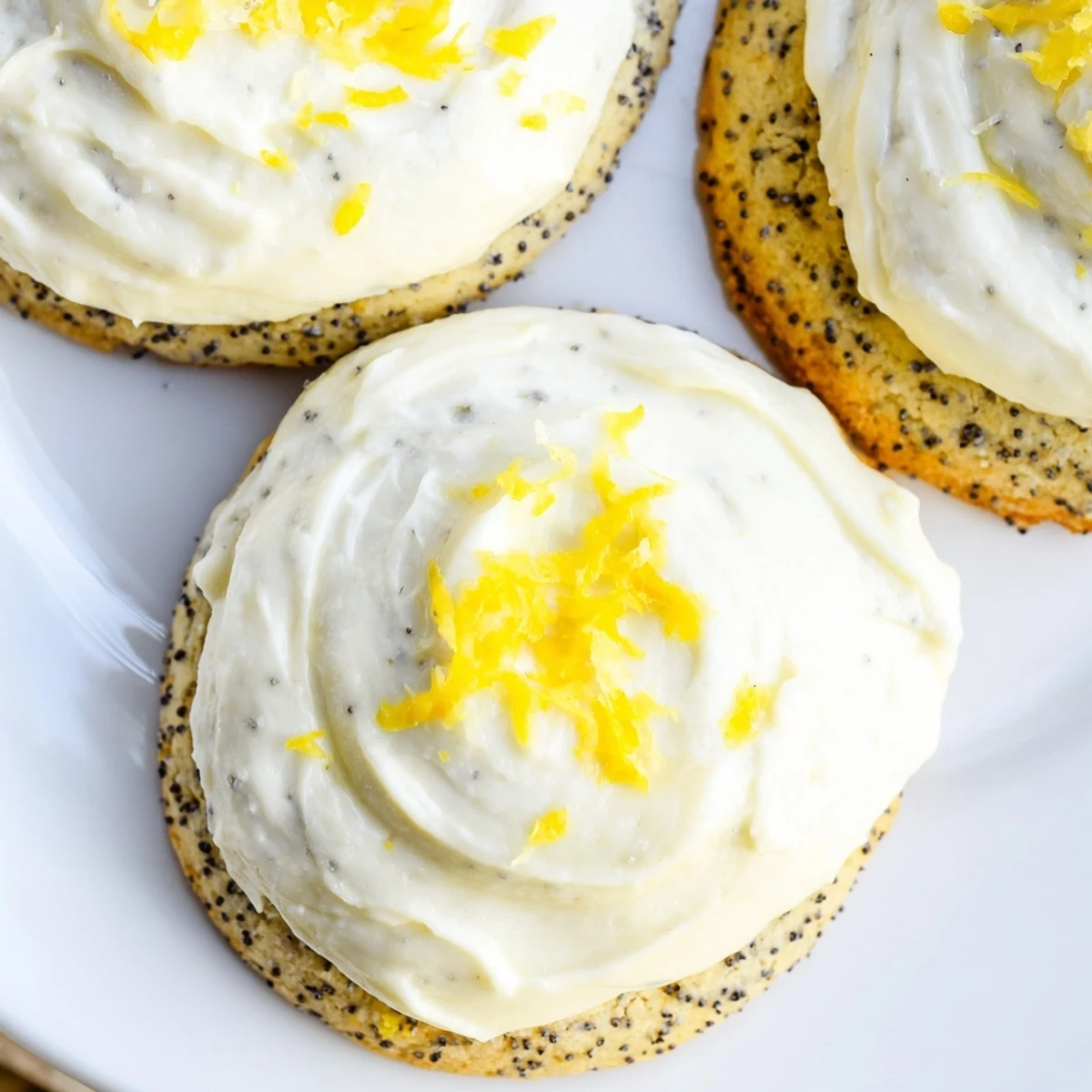 Soft buttery lemon cookies topped with creamy cheesecake frosting and poppy seed speckles
