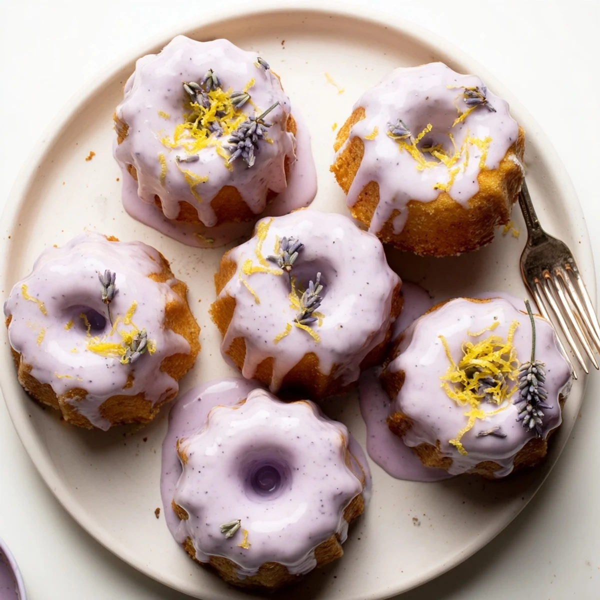 Teatime mini lemon cakes topped with floral lavender icing and garnished with lemon zest