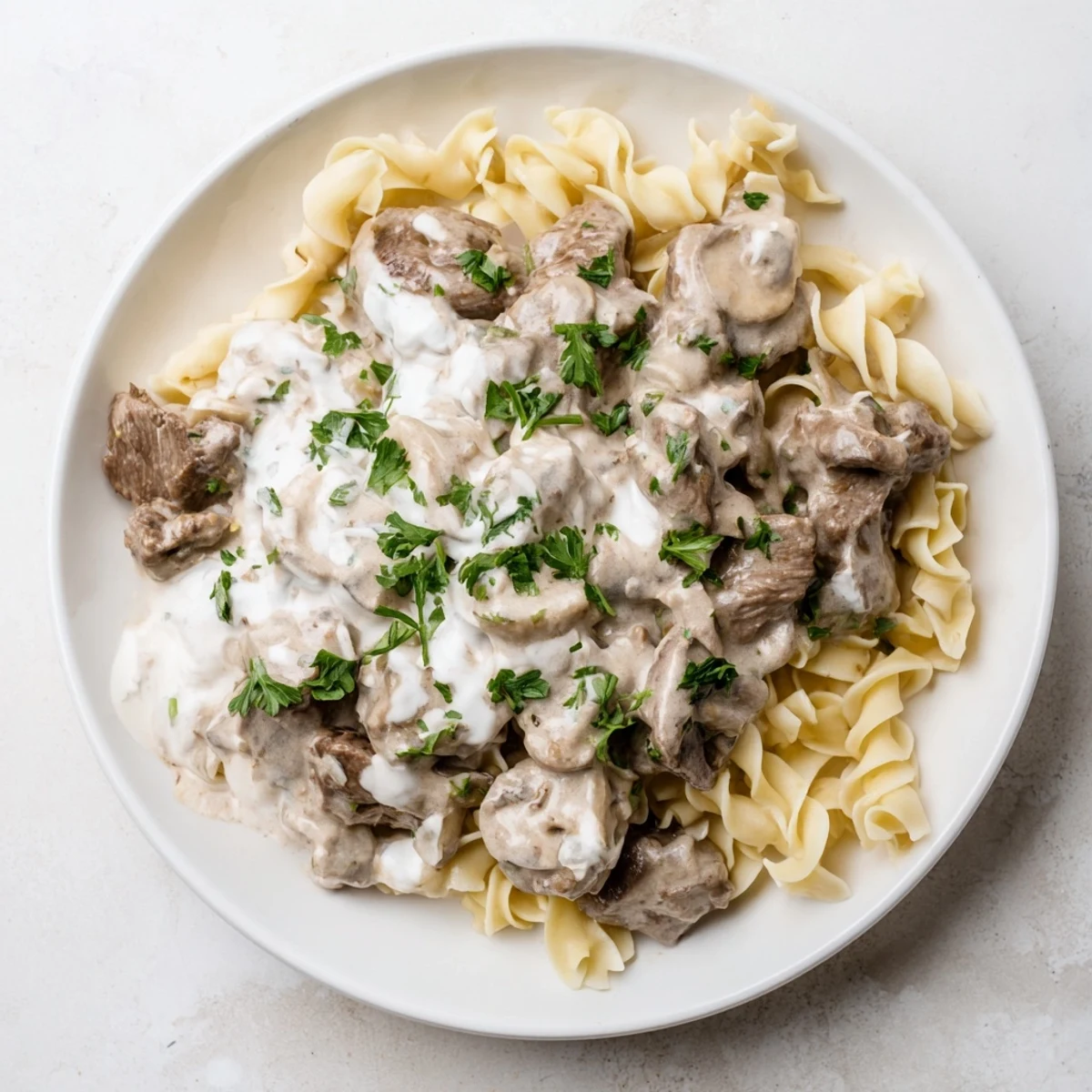 Creamy beef stroganoff with tender beef strips and mushrooms served over egg noodles