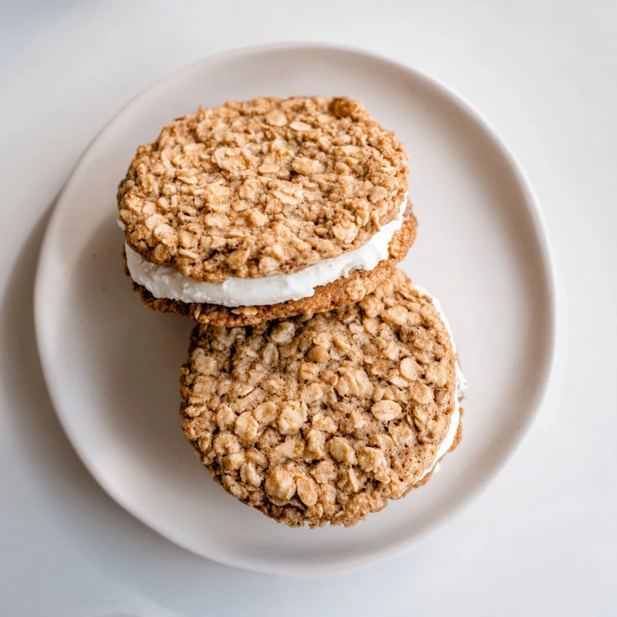 Soft homemade oatmeal cream pies with fluffy vanilla frosting sandwiched between chewy golden-brown cookies