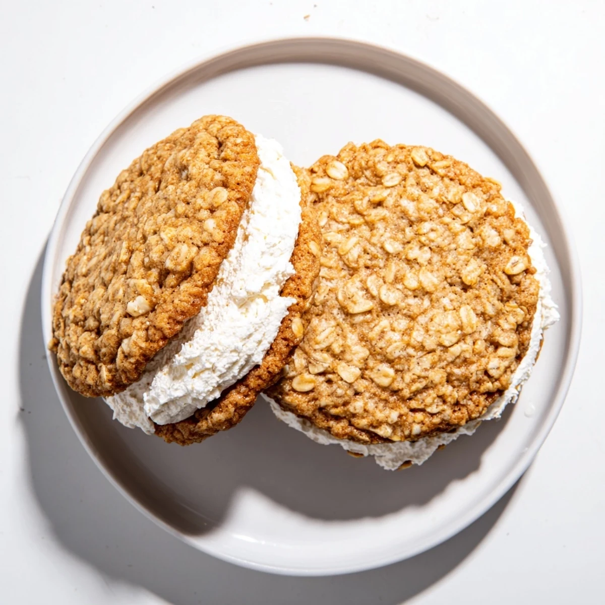 Two chewy oatmeal cookies filled with thick white cream creating the perfect homemade oatmeal cream pies