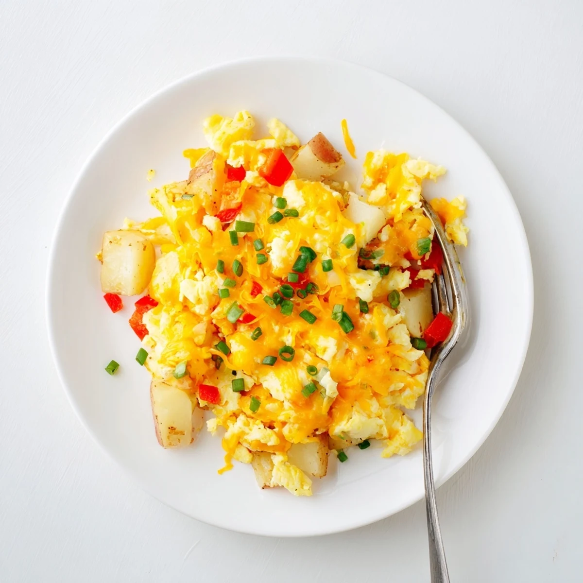 Hearty breakfast of scrambled eggs mixed with crispy potatoes and melted cheese topping