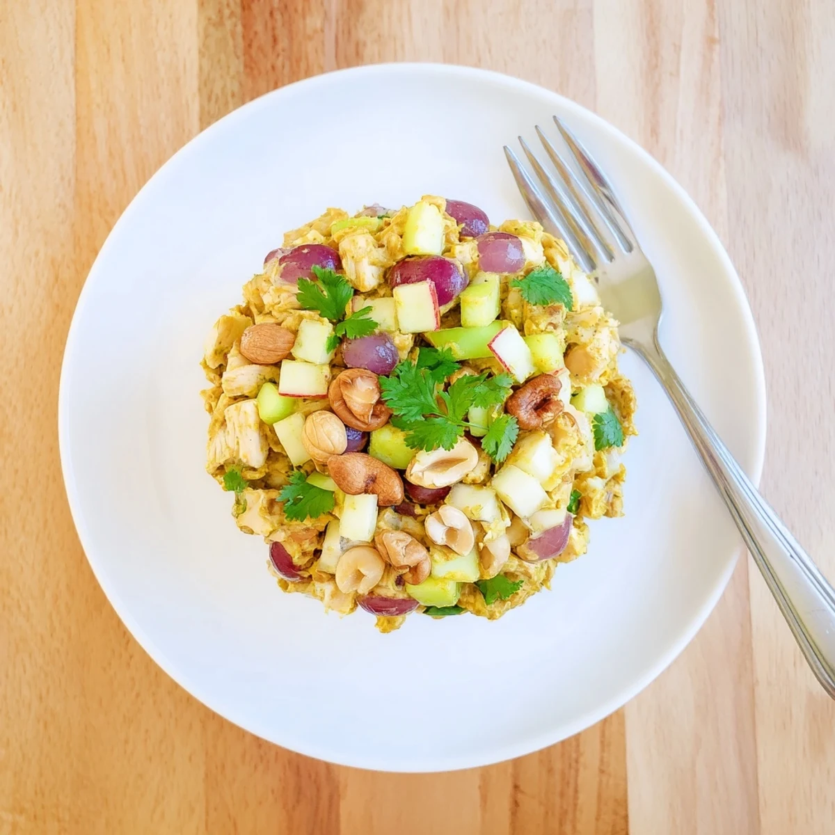 Vibrant chicken salad featuring diced chicken, red apples, cashews, and fresh herbs coated in a rich golden curry mayonnaise