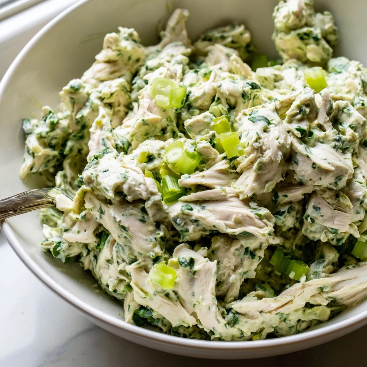 Creamy green goddess chicken salad dip served in a bowl with fresh herbs and crackers