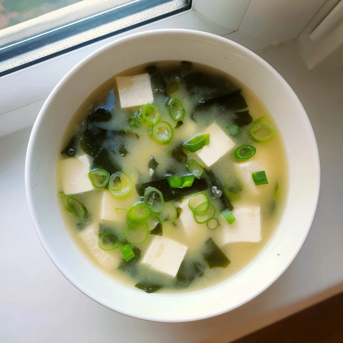 Steaming bowl of easy authentic miso soup with silken tofu cubes and bright green onion garnish