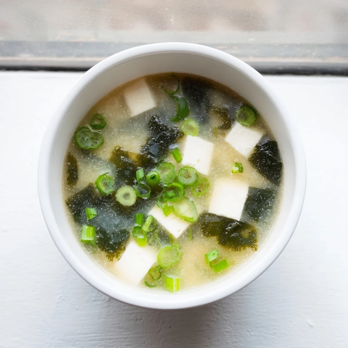Creamy easy authentic miso soup featuring tender tofu pieces and rehydrated wakame seaweed in light dashi broth