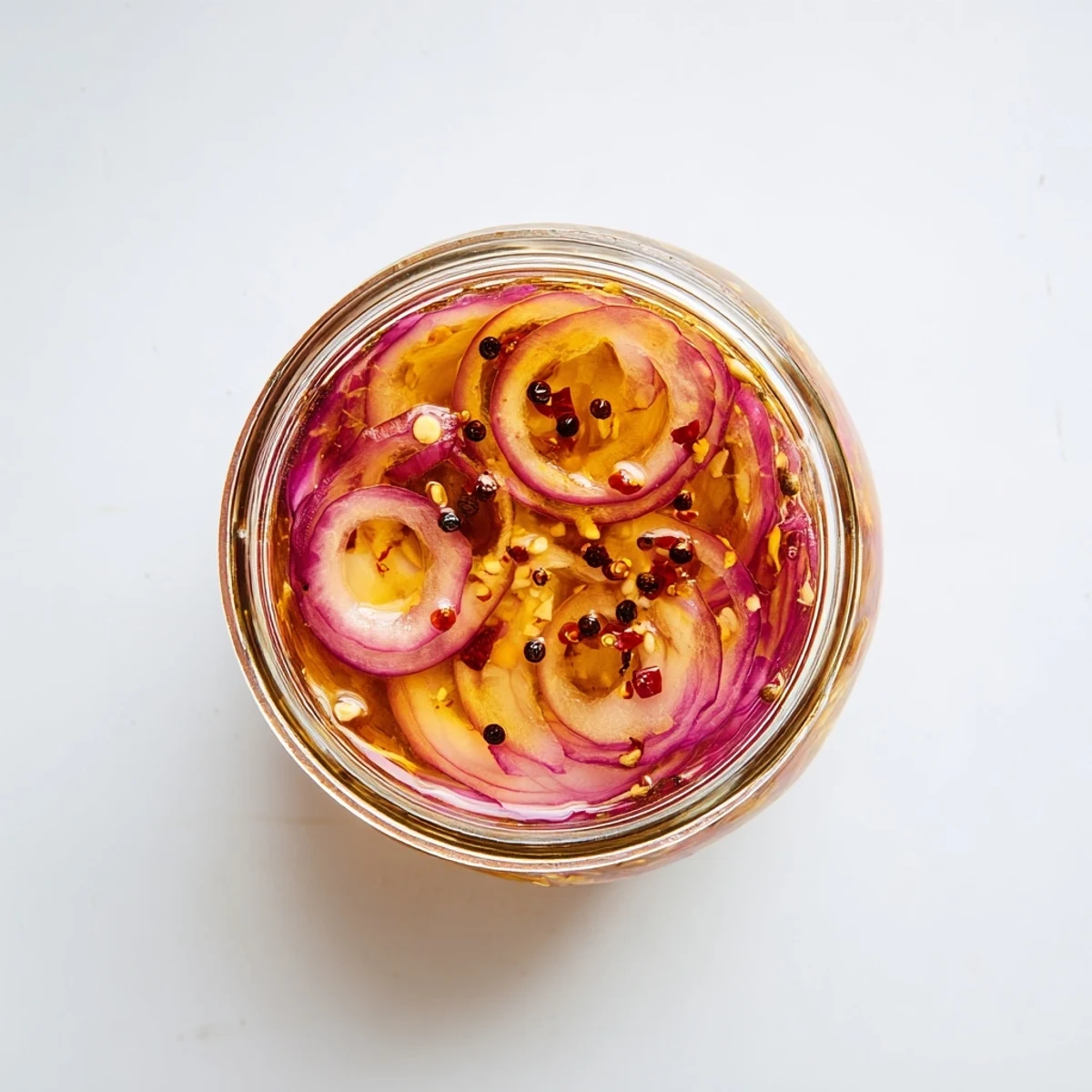Mason jar showcasing thinly sliced red onions pickled in sweet spicy hot honey mixture
