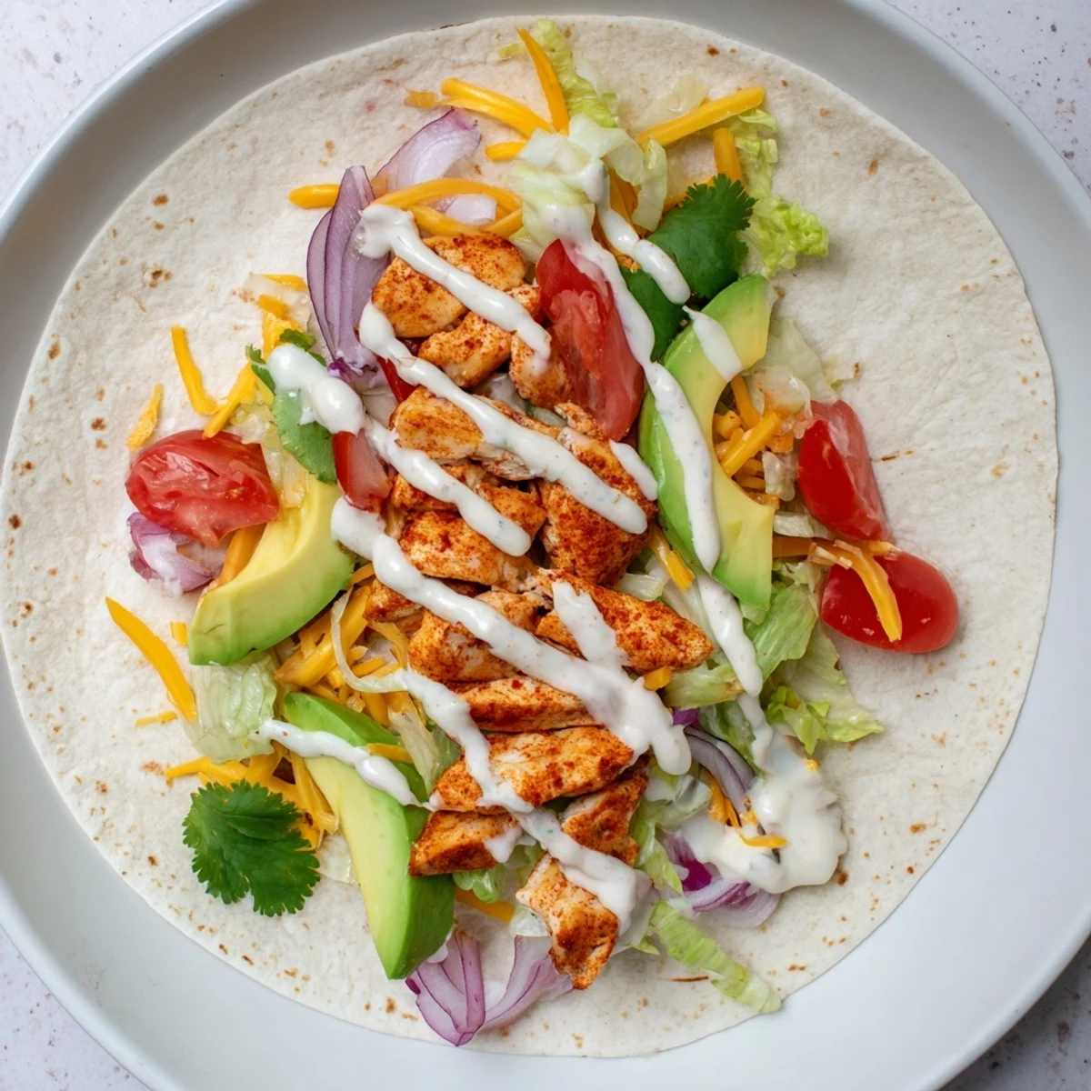 Hand-held lunch wrap stuffed with juicy spiced chicken breast, creamy avocado slices, and shredded cheddar cheese