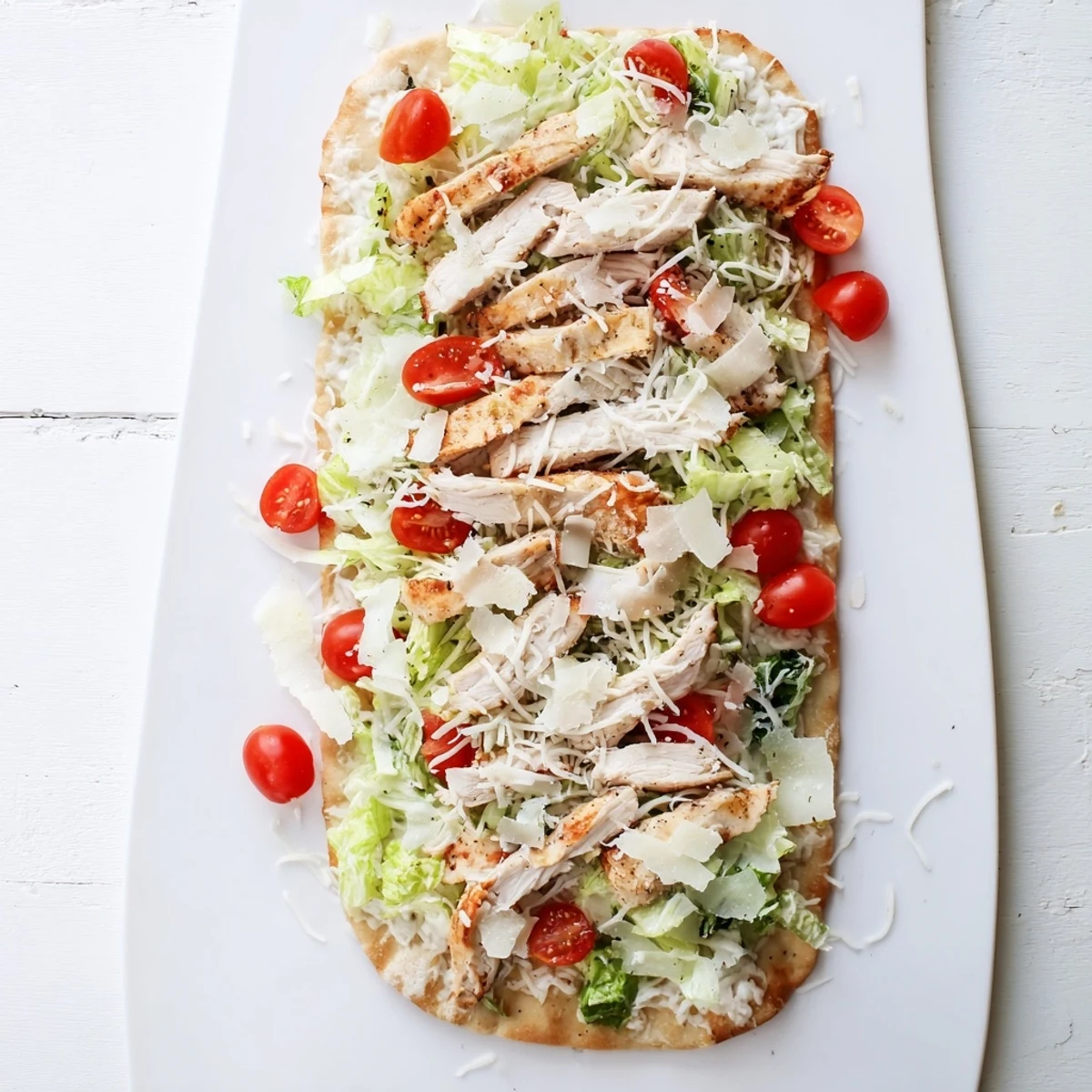 Sliced Chicken Caesar Flatbread topped with juicy seasoned chicken, fresh lettuce, and shaved parmesan on crispy baked flatbread