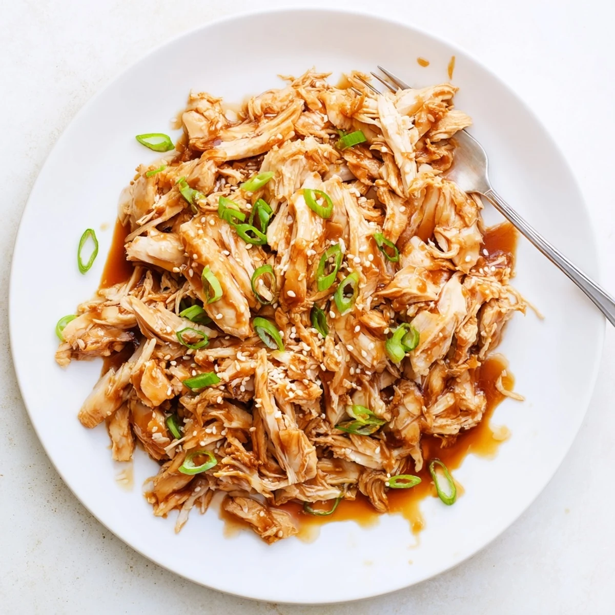 Slow cooker chicken thighs simmered in thick teriyaki sauce with sesame seed garnish