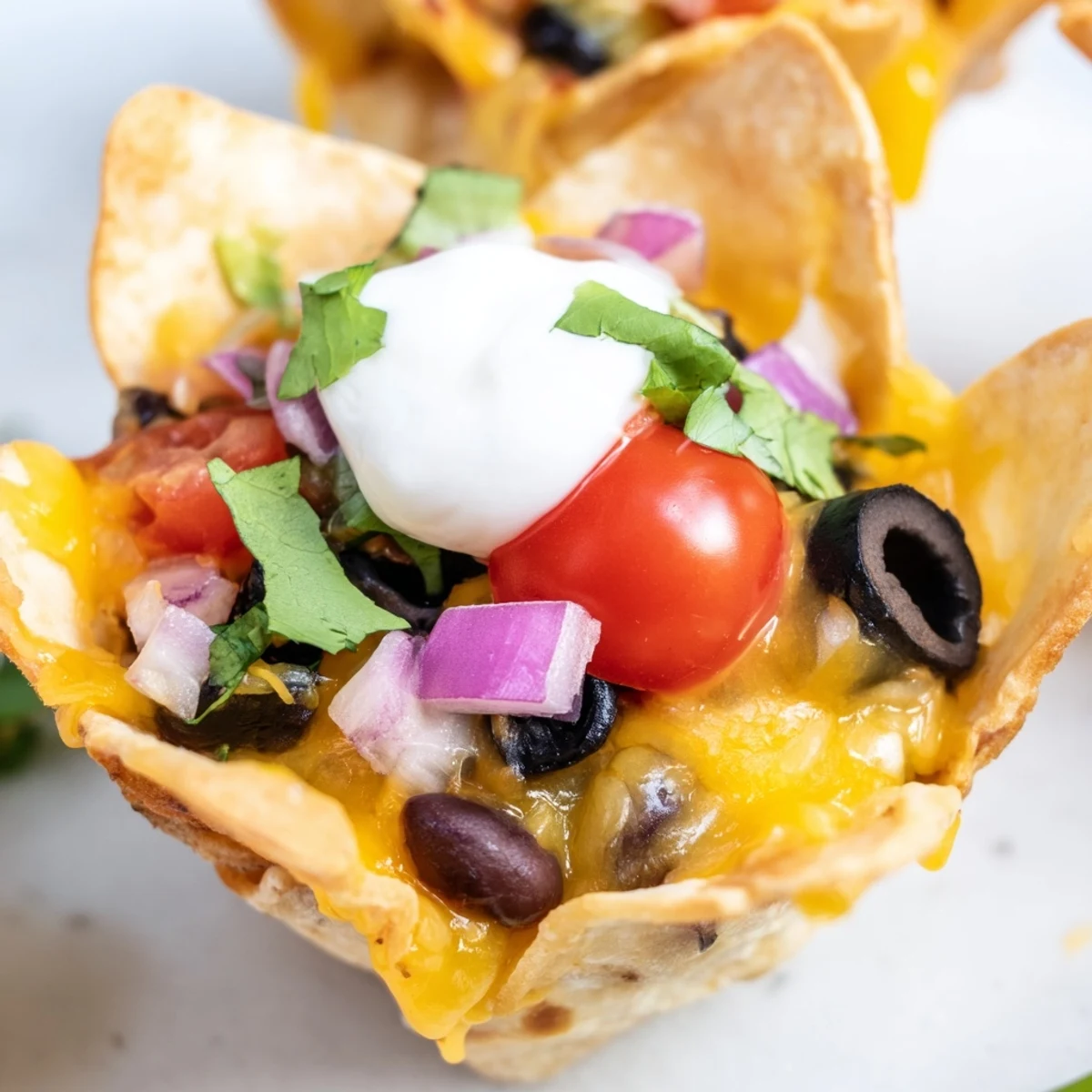 Crispy tortilla cups overflowing with gooey cheddar, black beans, and zesty jalapeño slices ready to serve.