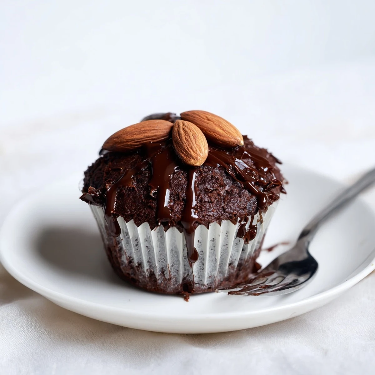 Rich Flourless Almond Joy Cupcakes drizzled with glossy chocolate and topped with roasted almonds