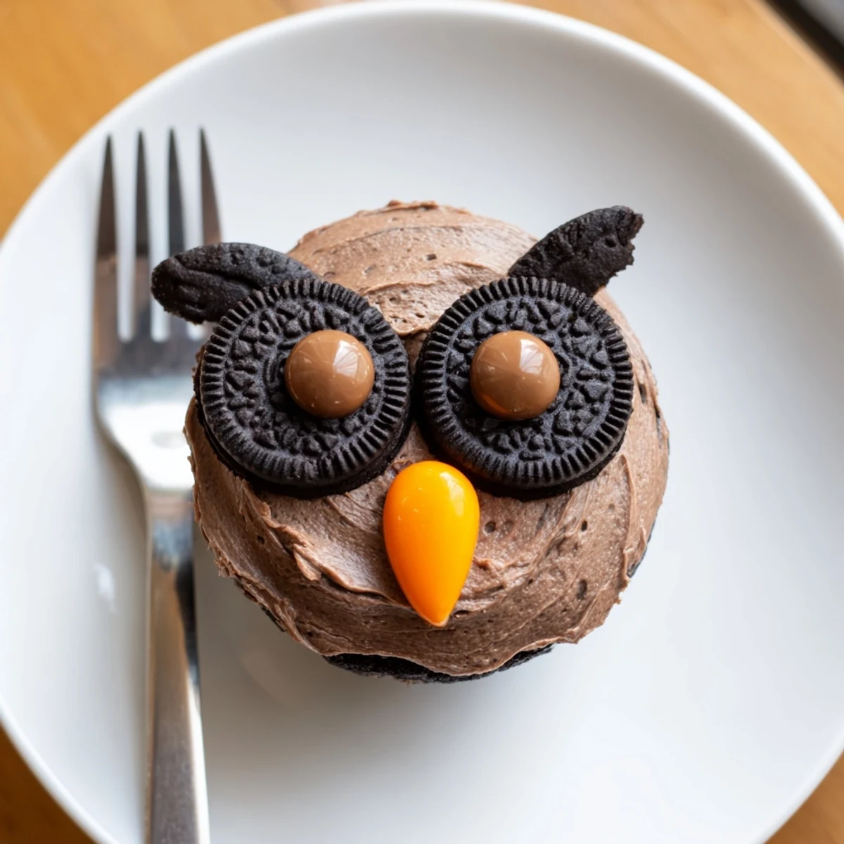 Adorable Oreo Owl Cupcakes topped with creamy chocolate frosting and candy eyes on a rustic serving plate