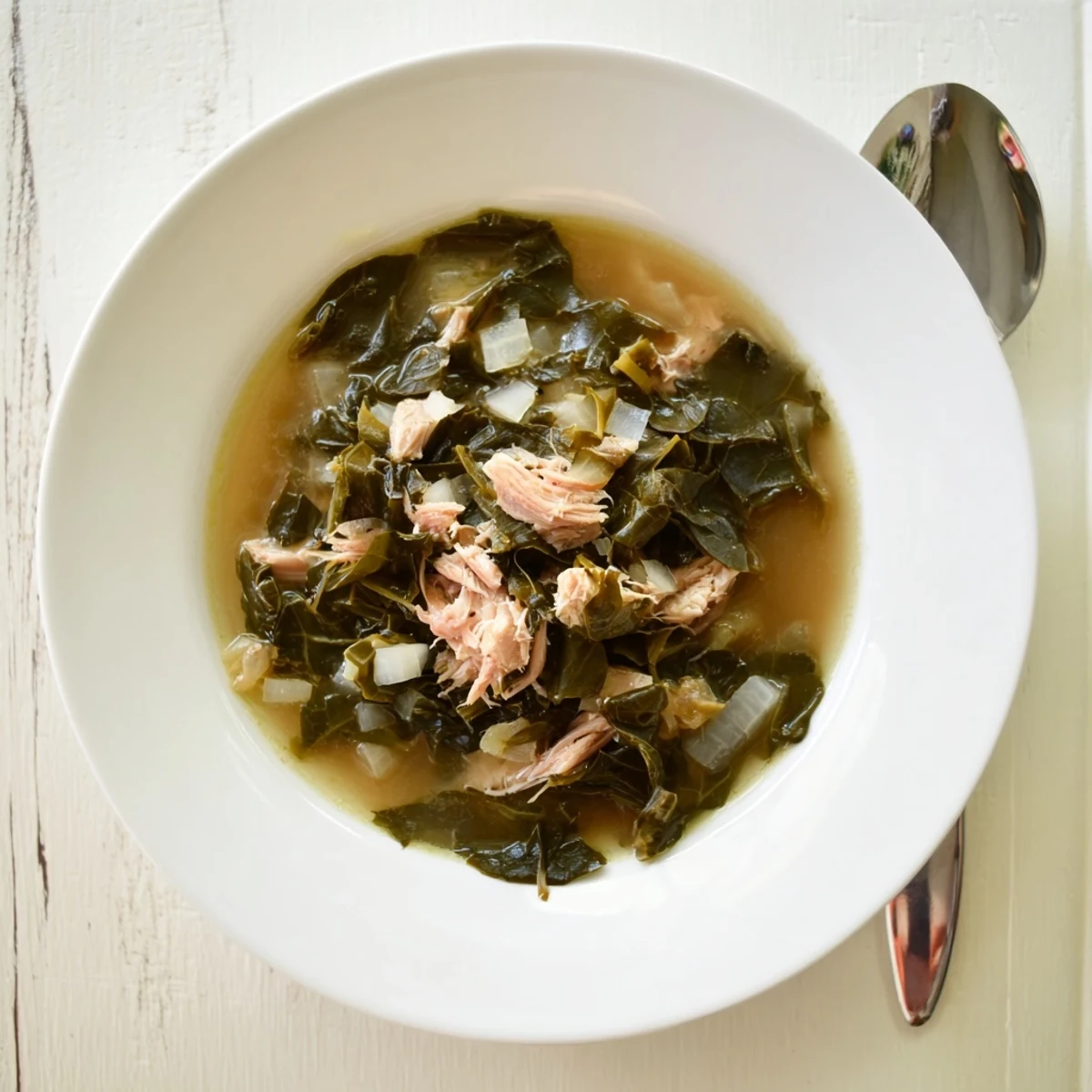 Golden bowl of tender slow-cooked Southern collard greens with smoky broth and shredded meat