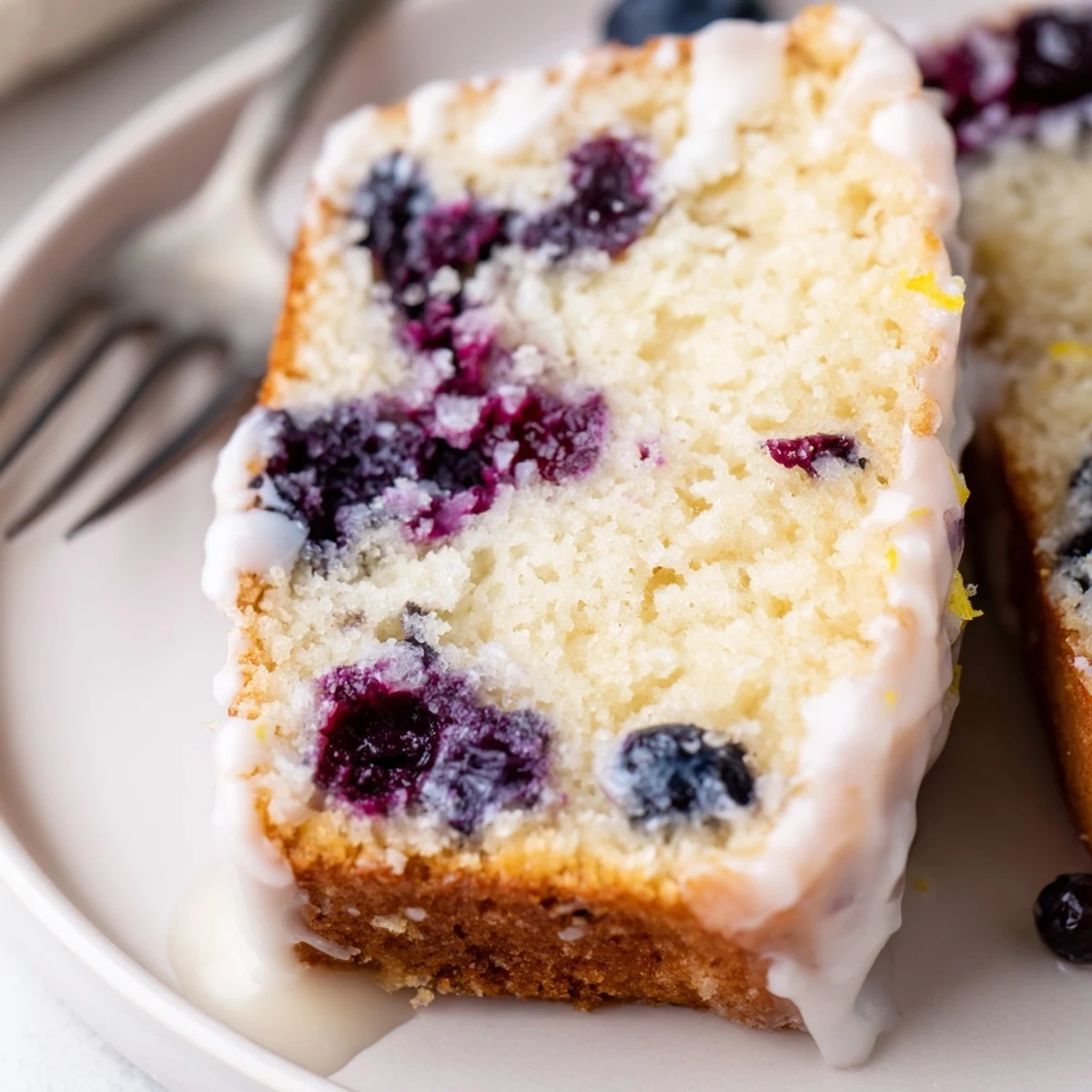 Moist lemon blueberry cake drizzled with tangy glaze and fresh blueberries on top