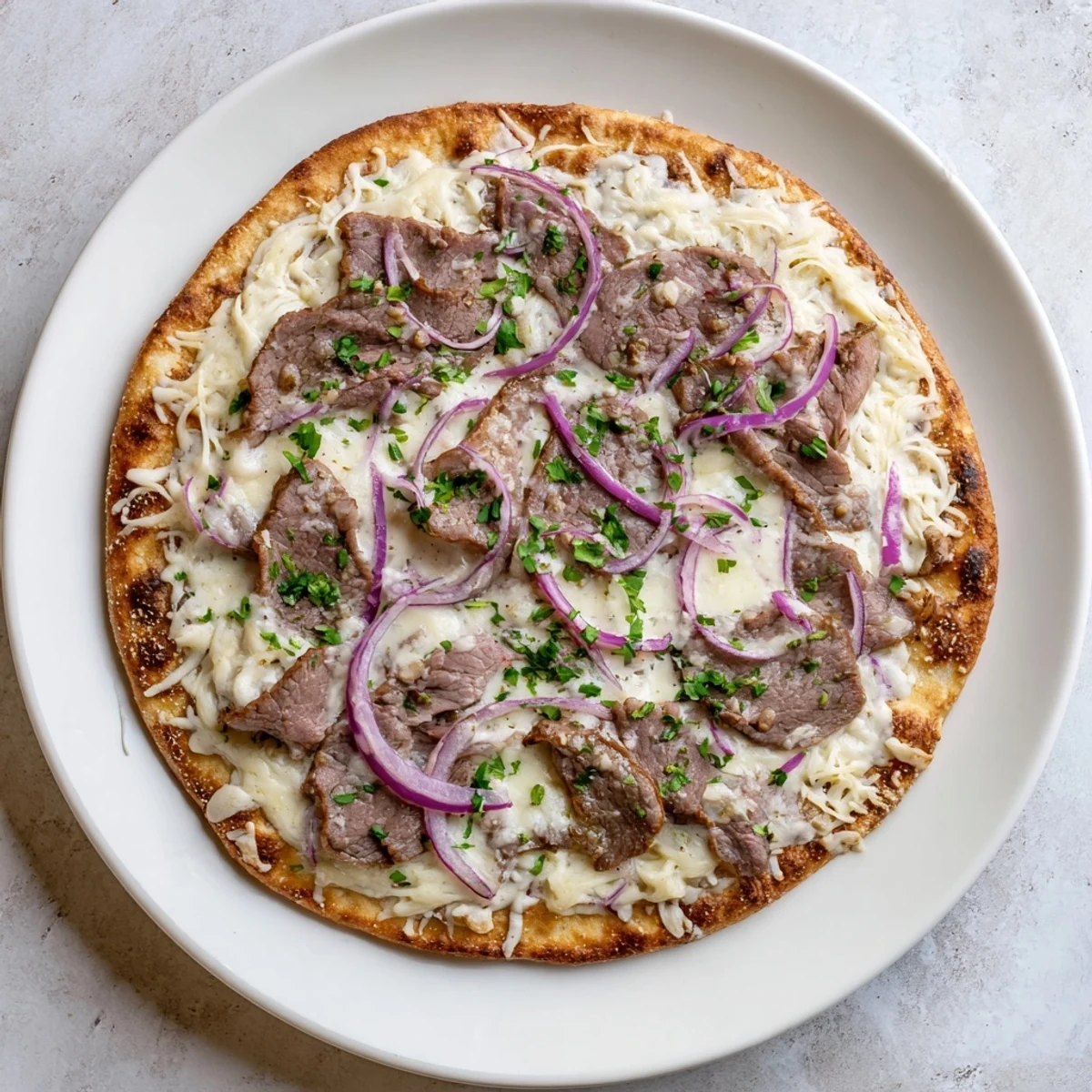 Golden Beef Alfredo Pizza with melted cheeses, tender beef slices, and fresh parsley garnish on a bubbling white sauce base