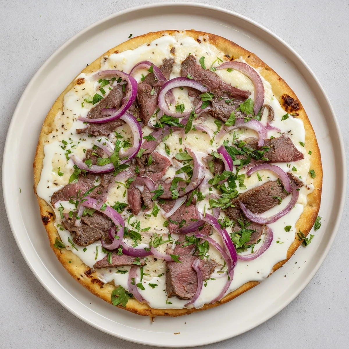 Homemade Beef Alfredo Pizza baked to golden perfection with rich Parmesan cream sauce, seared sirloin, and melted shredded cheeses