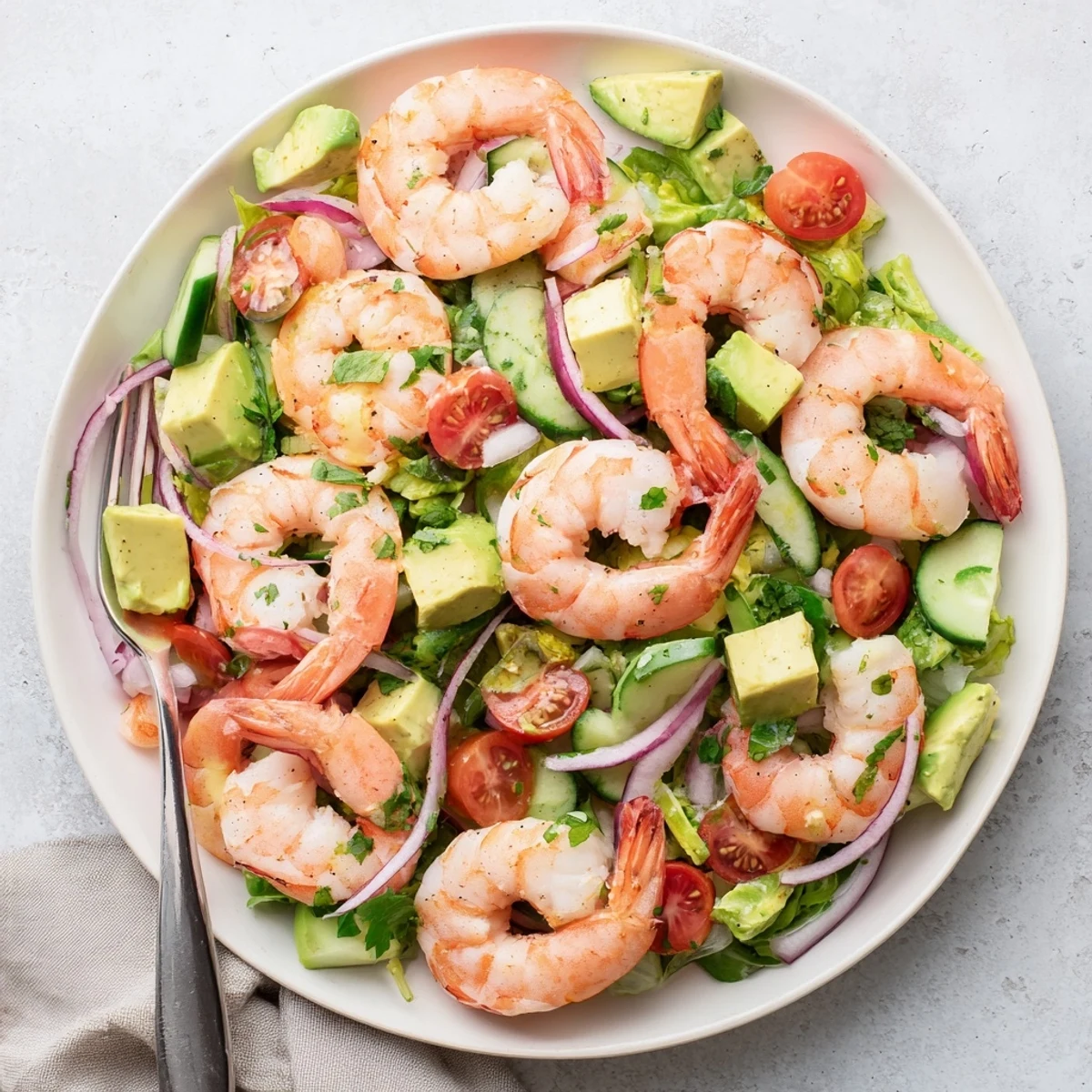 Colorful bowl of succulent shrimp and creamy avocado salad with cilantro and cucumber slices