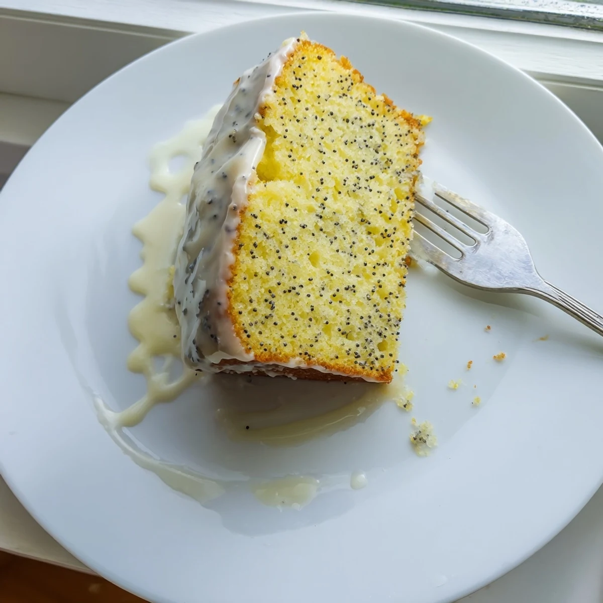 Golden lemon poppy seed loaf cake drizzled with sweet white citrus glaze on serving plate