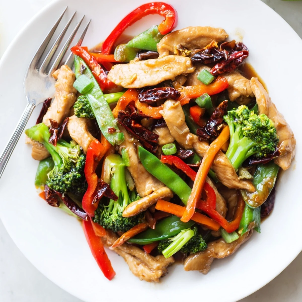 Glossy Hunan Chicken served over steamed rice with bright broccoli and scallions
