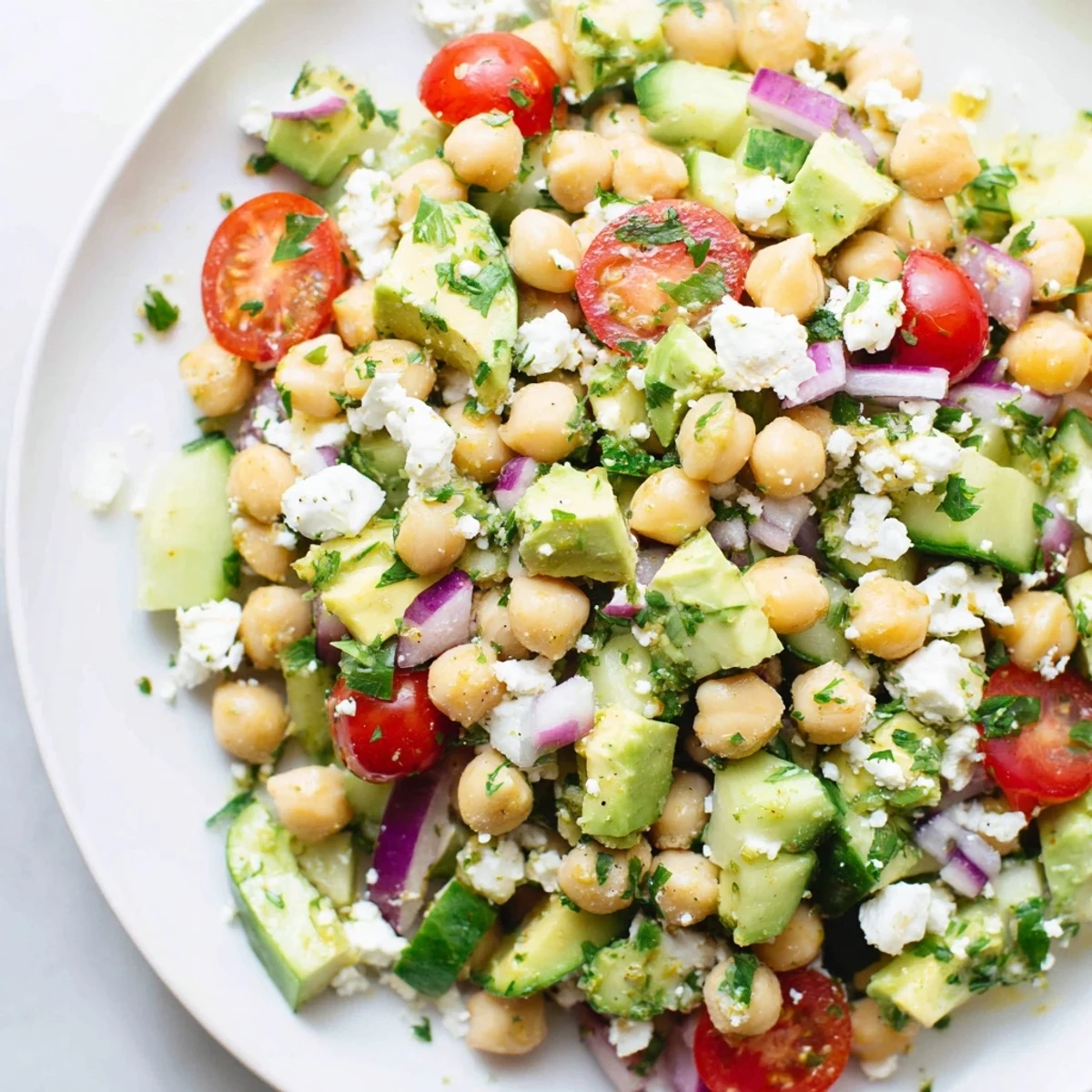Chickpea feta avocado salad in a rustic bowl drizzled with bright lemon herb dressing