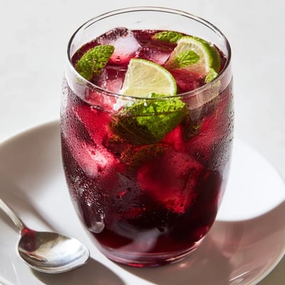 Refreshing Hibiscus Iced Tea with Lime Slices poured over ice, showing a vibrant ruby-red hue and fresh citrus wedges.