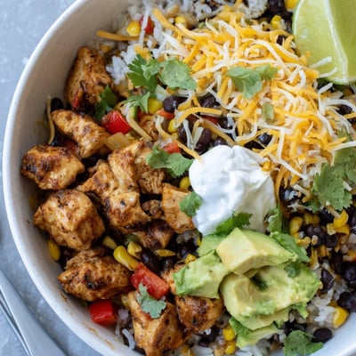 Steamy bowl of tender chicken and rice loaded with black beans, corn, and melted cheddar cheese