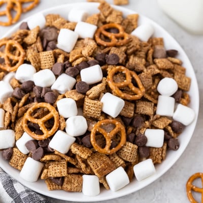 A bowl filled with crunchy graham crackers, fluffy marshmallows, and pretzels covered in chocolate for this easy s'mores snack mix