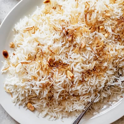 Steaming plate of buttery Lebanese rice alongside grilled kebabs and vegetables